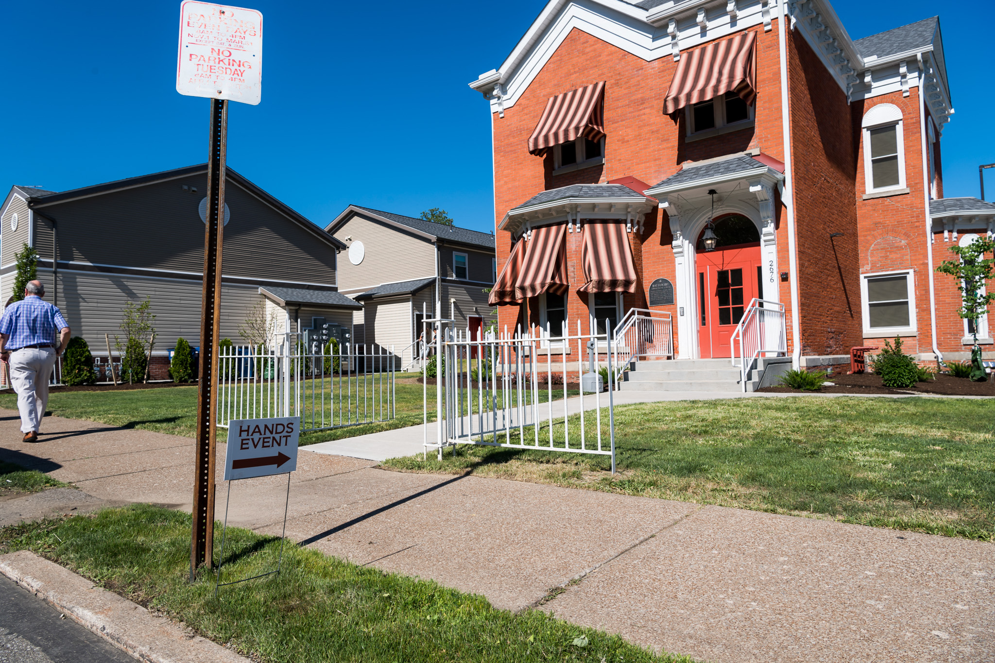 a man walking past a house with a sign in front of it